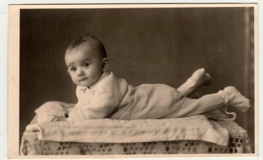 Retro fotoğraf yürümeye başlayan çocuk gösterir, yüzükoyun yat. Vintage siyah ve beyaz fotoğraf.