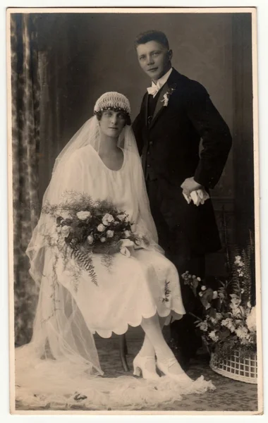 Vintage foto toont jonggehuwden. Huwelijksceremonie-bruid en bruidegom. Bruid draagt witte sluier en houdt bruiloft bloemen. Retro zwart & wit fotografie. — Stockfoto