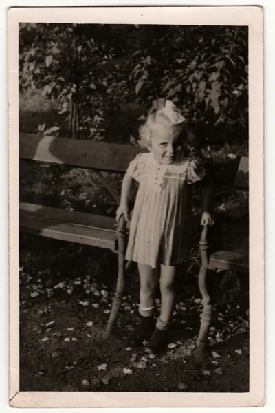 Ein altes Foto zeigt ein kleines Mädchen zwischen Parkbänken. Retro Schwarz-Weiß-Fotografie. — Stockfoto