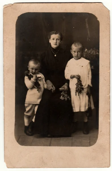 Foto vintage mostra la donna ei suoi figli in uno studio fotografico. Il ragazzo indossa un costume da marinaio e un vestito bianco da ragazza. Fotografia retrò in bianco e nero con effetto seppia . — Foto Stock