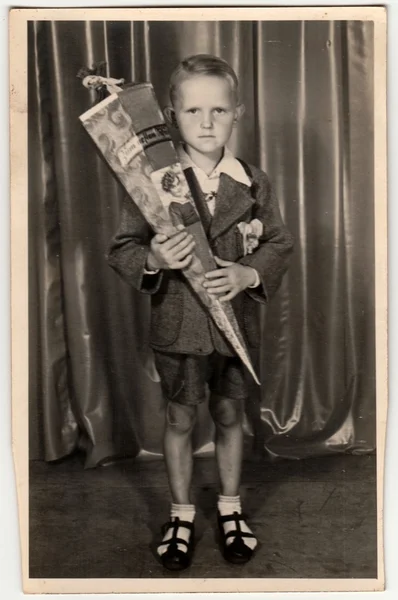 Photo vintage montre élève garçon avec "Schultute" ou cône d'école, bonbons pour le premier jour à l'école. Photo studio avec teinte sépia . — Photo