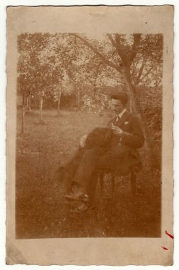 Vintage fotoğraf adam bahçede bir sandalyeye oturur gösterir. Sepya etkisi ile retro siyah ve beyaz fotoğrafçılık.