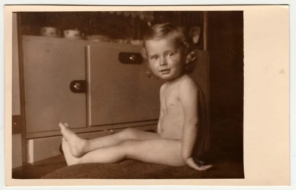 Vintage fotó azt mutatja, egy kis fiú-meztelen kisgyermek. A szekrény a háttérben van. Retro fekete reggeli fehér fotózás. — Stock Fotó