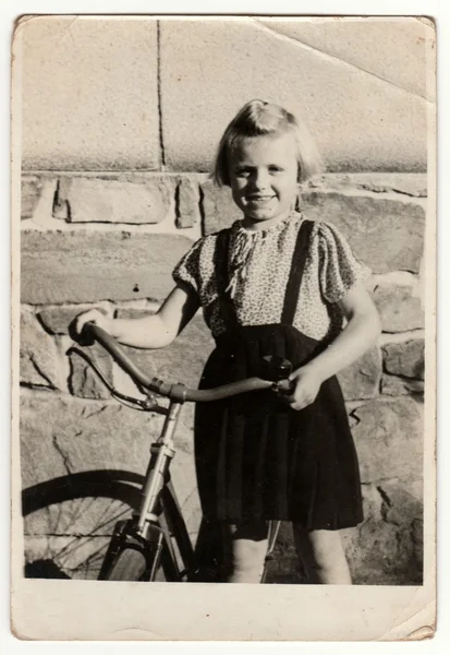 Vintage fotoğraf bisikletile küçük bir kız gösterir. Retro siyah & beyaz fotoğraf.