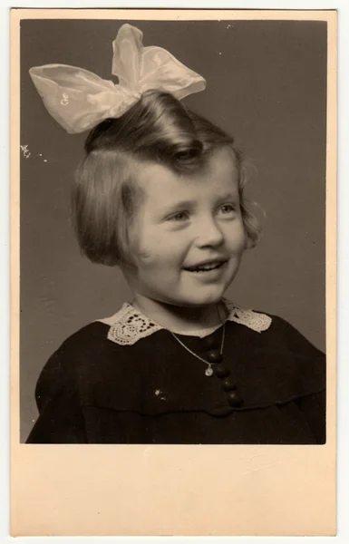 Vintage fotó azt mutatja, a portré egy kis aranyos lány szalaggal a haját. Retro fekete reggeli fehér fotózás. — Stock Fotó