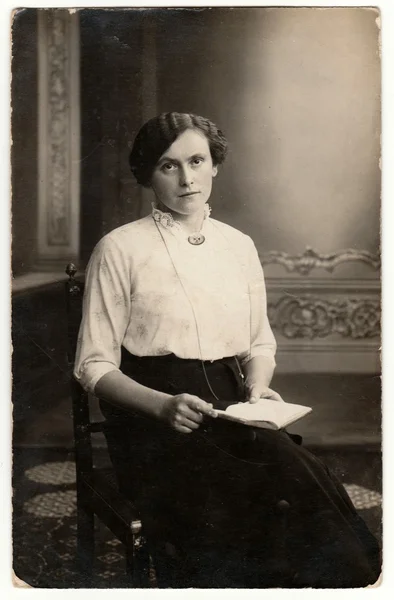 Vintage photo shows a young woman. She wears Edwardian hairstyle. Retro black & white studio photography with sepia effect. — Stock Photo, Image