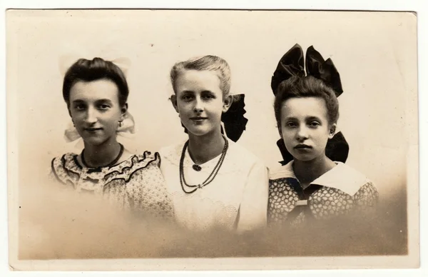 Foto vintage muestra un grupo de chicas posa en el estudio de fotografía. Las niñas usan cinta para el cabello y algunas de ellas tienen collar (cadena de cuentas). Fotografía en blanco y negro retro con efecto sepia . — Foto de Stock