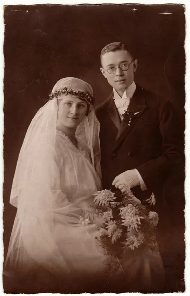 Vintage photo shows newlyweds. Groom wears glasses and bride wears long veil. Retro black & white wedding photography. — Stock Photo, Image