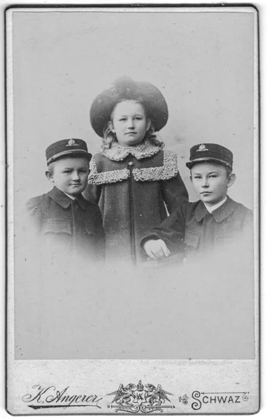 빈티지 캐비닛 카드는 귀여운 두 형제와 그녀의 여동생의 초상화를 보여준다. Edwardian 스타일. 사진은 사진관에서 찍었습니다. 사진은 오스트리아 - 헝가리 제국이나 오스트리아에서 찍은 것이다 — 스톡 사진