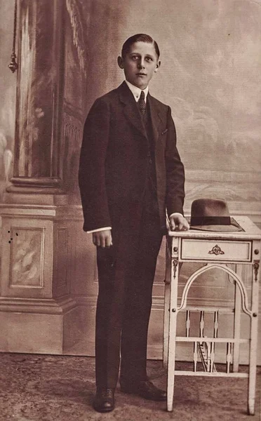 Фотографія Вінтеджа показує, що елегантний хлопчик носить чорний костюм. Чорно-біла антична фотографія. — стокове фото