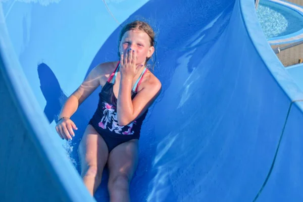 Chica deslizándose hacia abajo en un tobogán de agua en el parque acuático. Concepto de vacaciones. Diversión festiva —  Fotos de Stock