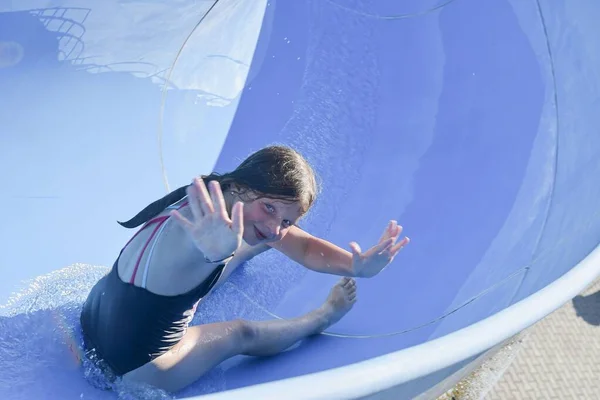 Pretty little girl sliding on water slide. Funny childrens attraction at water park. Vacation concept — Stock Photo, Image