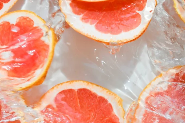 Primo piano fette fresche di pompelmo rosso su sfondo bianco. Fette di pompelmo in acqua frizzante su fondo bianco, primo piano. Soda agli agrumi. Copia spazio — Foto Stock