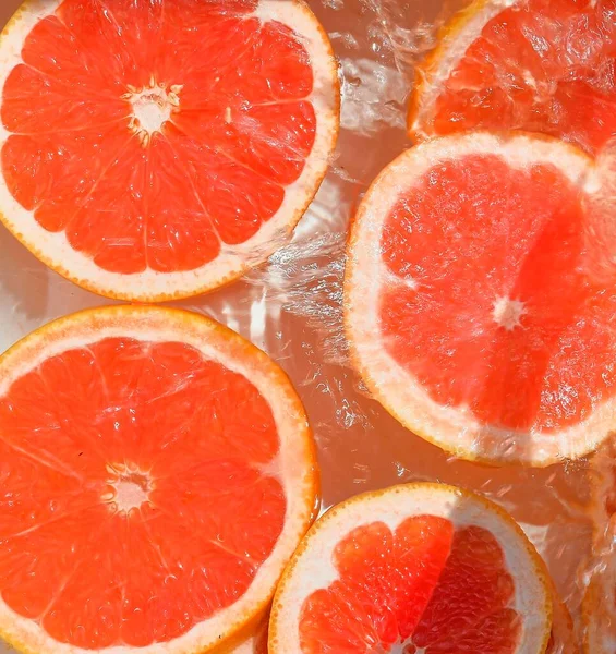 Vista de perto das fatias de toranja vermelha em fundo de limonada. Textura de arrefecer verões doces beber com bolhas macro na parede de vidro. Projeto plano — Fotografia de Stock