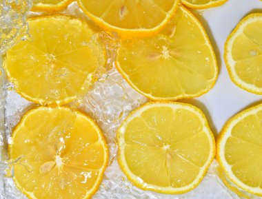 Beyaz arka planda suya limon dilimleri. Baloncuklu limonla yakından çek. Suda sarı olgun limon dilimleri. Sudaki meyvelerin makro görüntüsü