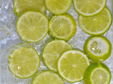 Beyaz arka planda taze limon dilimleri. Beyaz arka planda köpüklü suyla dilimler halinde limon dilimleri, yakın plan. Citrus gazozu