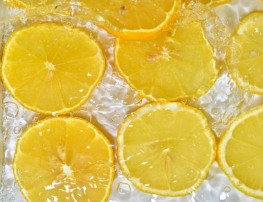 Beyaz arka planda taze sarı limon dilimleri. Beyaz arka planda köpüklü suda limon dilimleri, yakın plan. Citrus gazozu