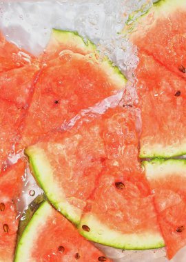 Beyaz arka planda taze kırmızı kavun dilimleri. Beyaz arka planda köpüklü suda kavun dilimleri, yakın plan. Boşluğu kopyala