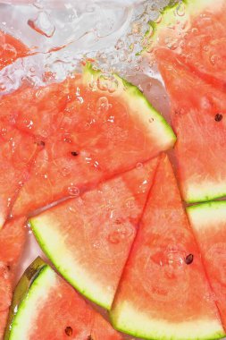 Beyaz arka planda taze kırmızı kavun dilimleri. Beyaz arka planda köpüklü suda kavun dilimleri, yakın plan. Boşluğu kopyala