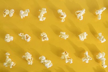 Pastel sarısı arka planda patlamış mısır yakın plan. Sarı retro arka planda pofuduk patlamış mısır içeren sinema konsepti