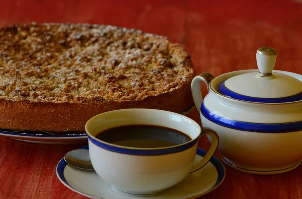 Сливовий розсипчастий пиріг з чашкою кави та цукровою чашкою на червоному фоні . — стокове фото