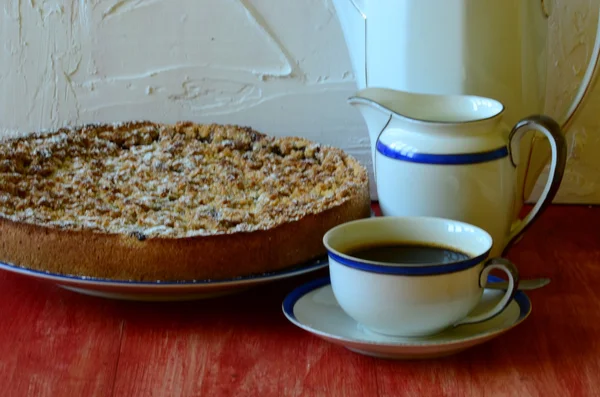 Plum crumble tart with cup of coffee, creamer, sugar bowl and coffee pot — Stock Photo, Image