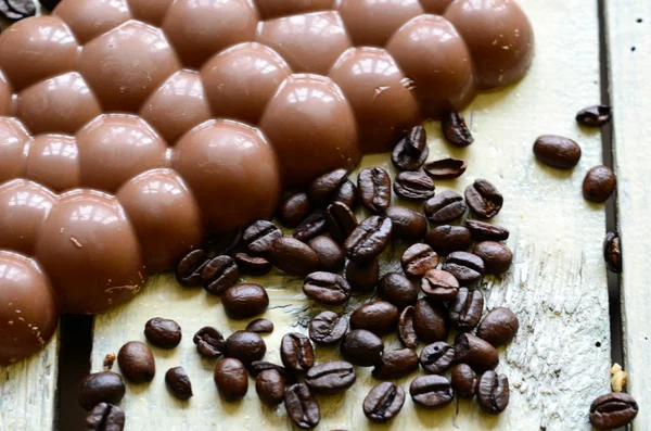 Granos de café con glaseado de chocolate y chocolate negro sobre fondo de madera . — Foto de Stock