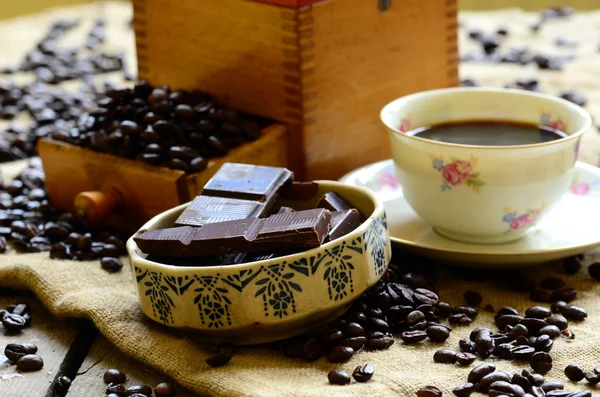 Granos de café con glaseado de chocolate y chocolate negro sobre fondo de madera . — Foto de Stock