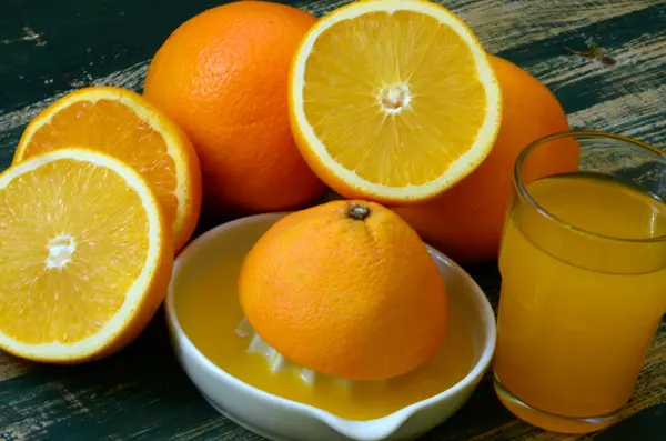 Bodegón de bellas artes con zumo de naranja y exprimidor de porcelana sobre mesa de madera . — Foto de Stock