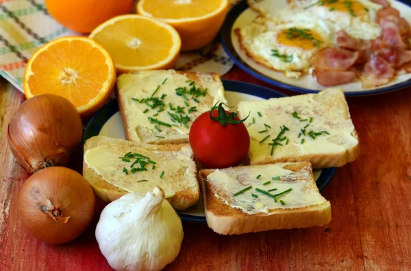 Desayuno rústico - pan tostado con mantequilla y cebollino, huevos fritos y tocino — Foto de Stock