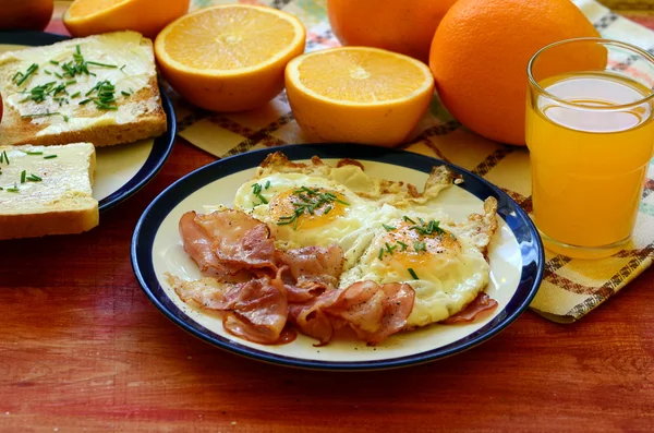 Café da manhã rústico - pão assado com manteiga e cebolinha, ovos fritos e bacon — Fotografia de Stock