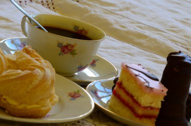 Beyaz masa örtüsü üzerinde kahve ile tatlılar.