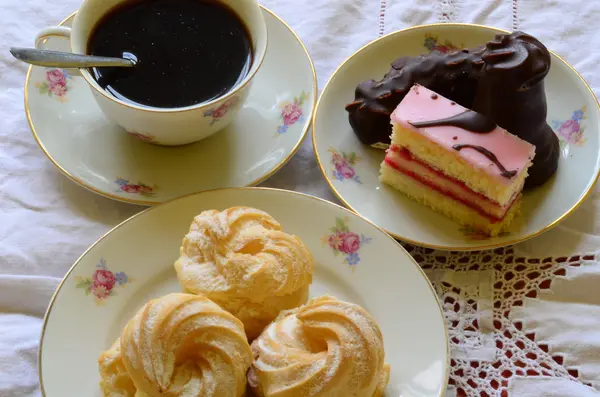 Desserter med kopp kaffe, kaffebönor och mandlar på vita duken. — Stockfoto