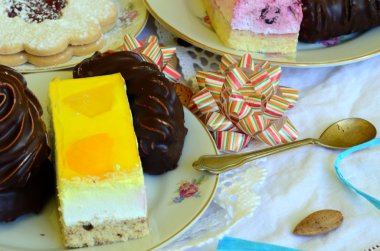 Fincan kahve, kahve çekirdekleri ve beyaz masa örtüsü üzerinde badem tatlılar.