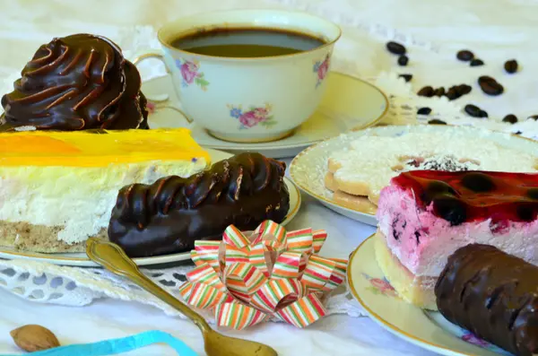 Desserter med kopp kaffe, kaffebönor och mandlar på vita duken. — Stockfoto