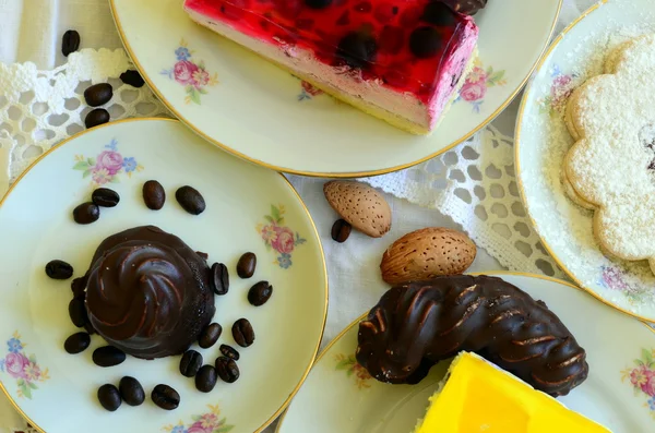 Desserts met kopje koffie, koffiebonen en amandelen op wit tafellaken. — Stockfoto