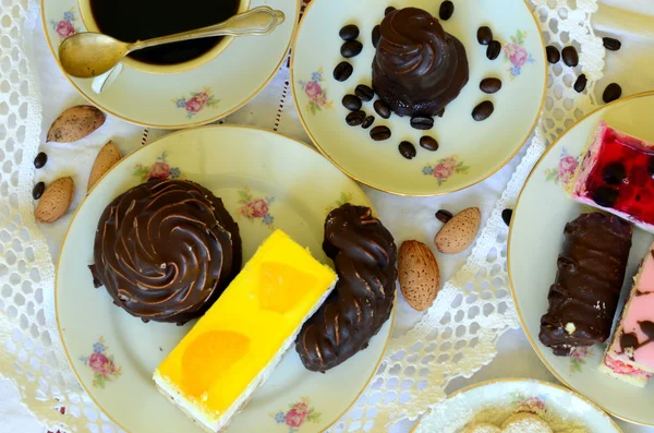 Desserter med kopp kaffe, kaffebönor och mandlar på vita duken. — Stockfoto