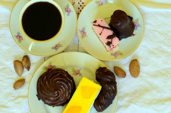 Десерты с чашкой кофе, кофейных зерен и миндаля на белой скатерти . — стоковое фото