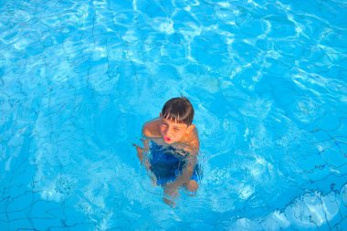 Halka açık yüzme havuzunda suda bir çocuk. Küçük bir çocuk havuzda oynuyor. Uzayı kopyala Yaz, yaz tatili ve eğlence konsepti.