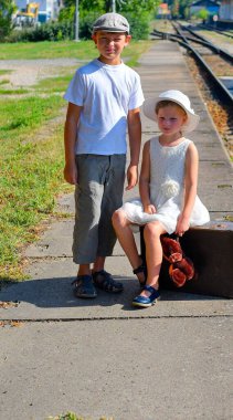 Tren peronundaki sevimli kardeşler. Küçük bir kız ve erkek tatil için seyahat ederler. Yolculuk, tatil ve tasasız çocukluk kavramı. Eski ve eski moda