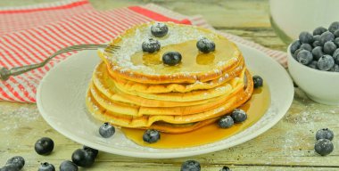Beyaz bir kırsal masada böğürtlenli ve akçaağaç şuruplu şekerli Amerikan krepleri. Kırsal alanda Amerikan gözlemeleri. Kolay Amerikan gözleme tarifi hafif ve tüylü krepler yapar. Özel bir kahvaltı hazırlamak için birebirdir.