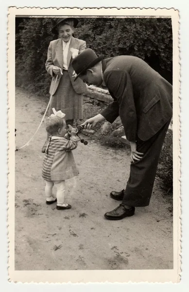 Винтажное фото показывает маленькую девочку с игрушкой во время прогулки, около 1942 года. . — стоковое фото