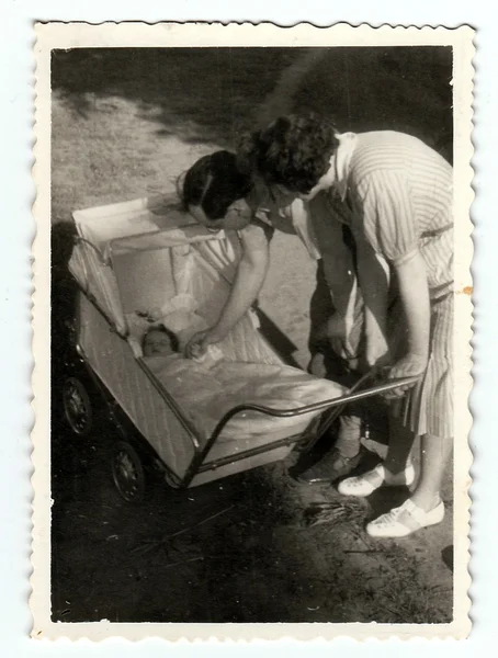 Foto vintage mostra bebê menina em um carrinho de bebê com os pais, por volta de 1940 . — Fotografia de Stock