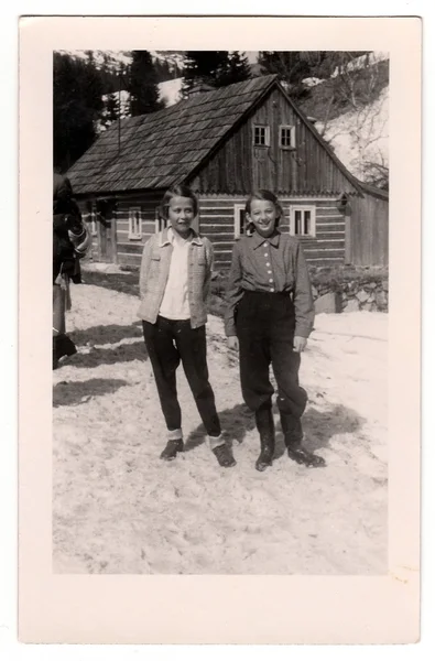 Ein Oldtimer-Foto zeigt zwei Mädchen im Winter vor einem Blockhaus — Stockfoto