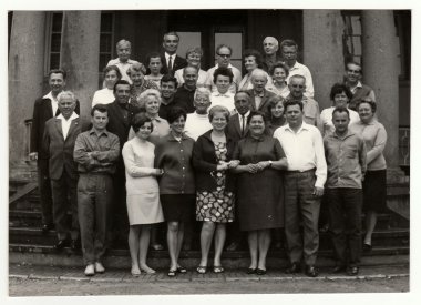 Vintage photo shows group of people in front of building, circa 1970s.