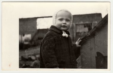 Vintage photo shows a small girl and kannel (doghouse), circa 1942.