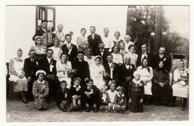 A vintage photo shows people in the back yard (during rural wedding feast), circa 1920.