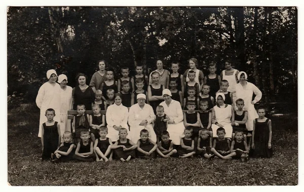 Foto vintage muestra un grupo de niños y enfermeras en la naturaleza. Foto tomada en el sanatorio, alrededor de la década de 1940 . — Foto de Stock