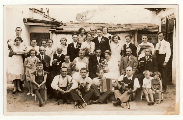 A vintage photo shows people in the back yard (during rural wedding feast), circa 1920. — Stock Fotó