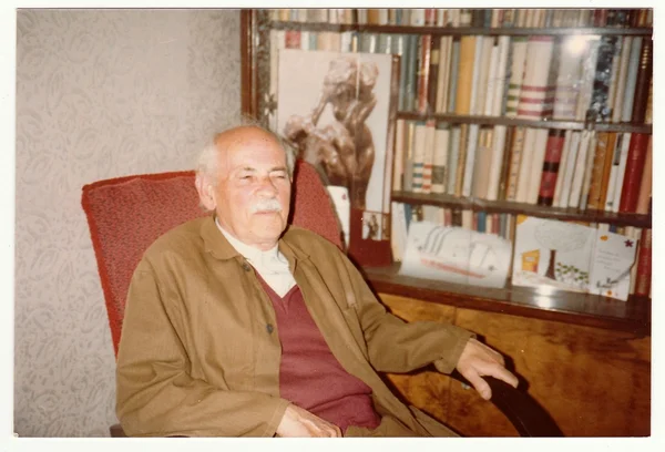 Vintage photo shows man sits on armchair, circa 1980s. — Stockfoto